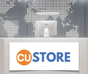 Computer sitting on flat surface with CUStore logo displayed on sign in front of it.